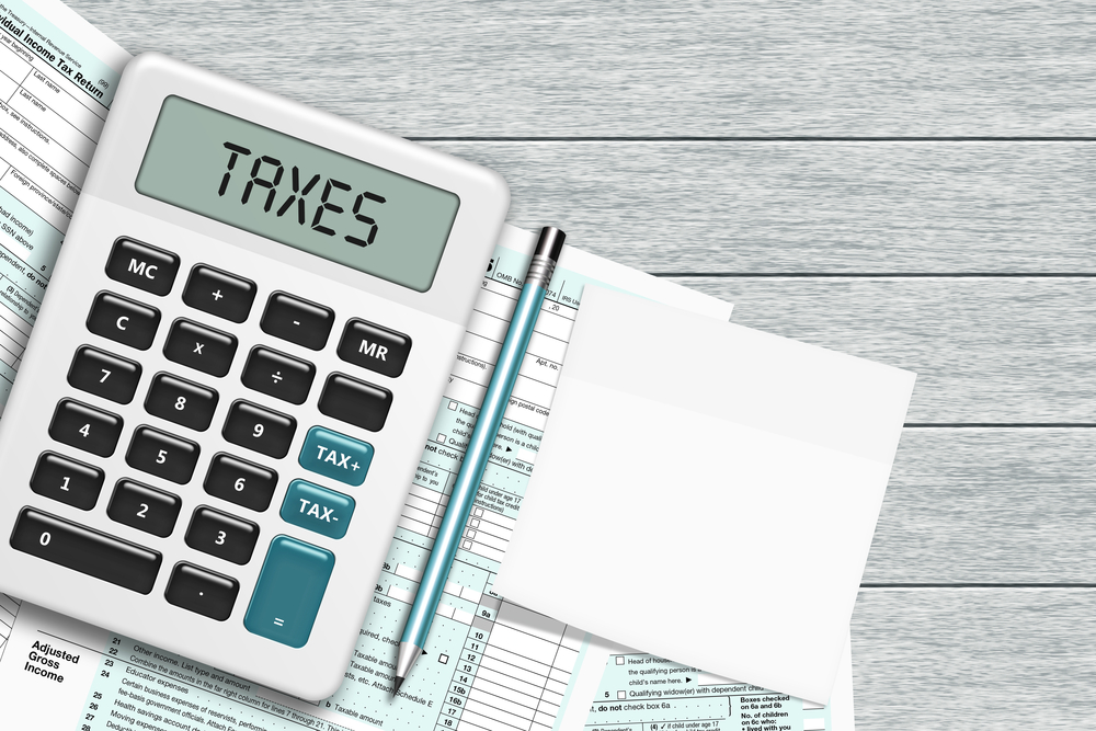 1040 tax form with calculator and note lying on wooden desk with place for text